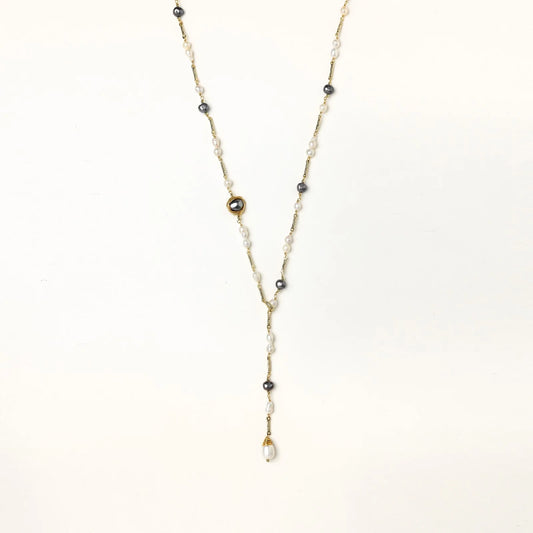 Y-shaped gold-plated necklace with white and gray freshwater pearls on cream background, showing adjustable drop design.