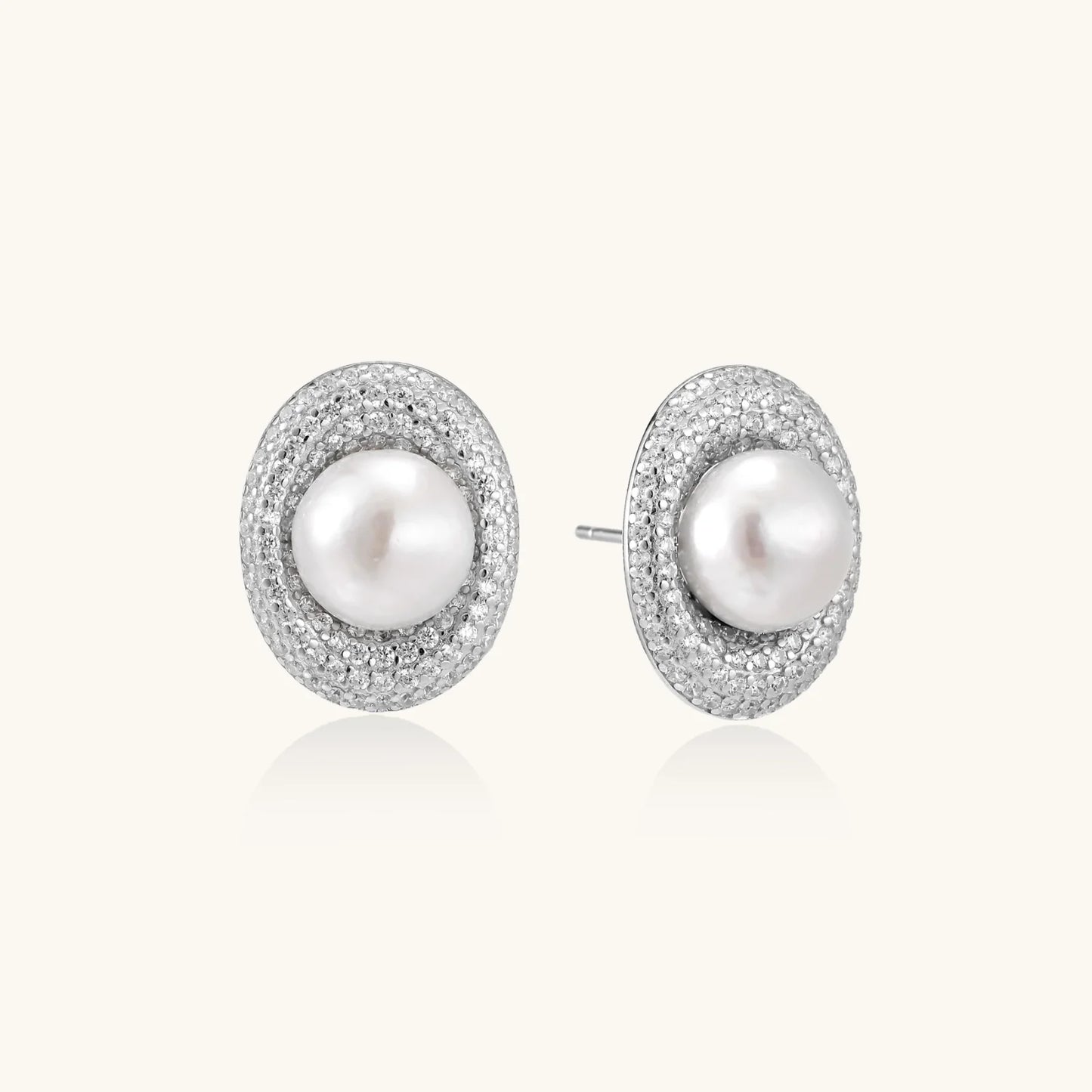 Oval rhodium-plated silver studs featuring freshwater pearls surrounded by pavé crystal halo on white background