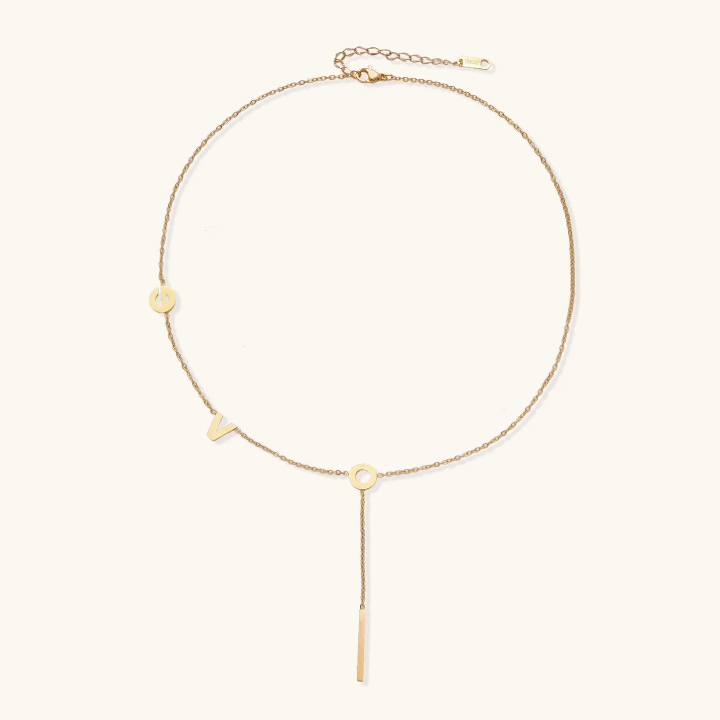 Gold Y-shaped necklace with L-O-V-E letter charms and vertical bar pendant on delicate chain against cream background